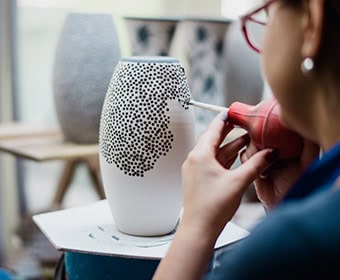 Vrouw die een keramische vaas beschildert bij Inclusief Jodendom.